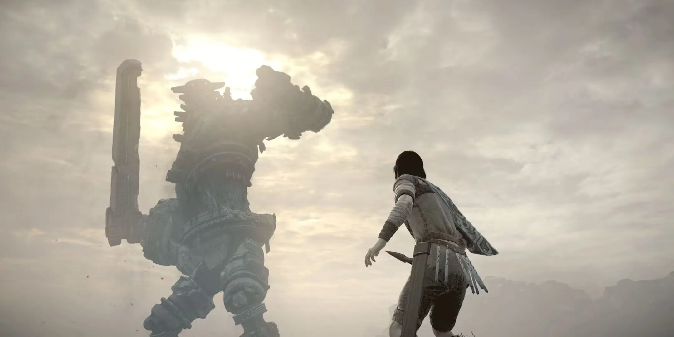 Nhân vật Wander trong Shadow Of The Colossus nhìn lên một Colossus khổng lồ với thanh kiếm sẵn sàng