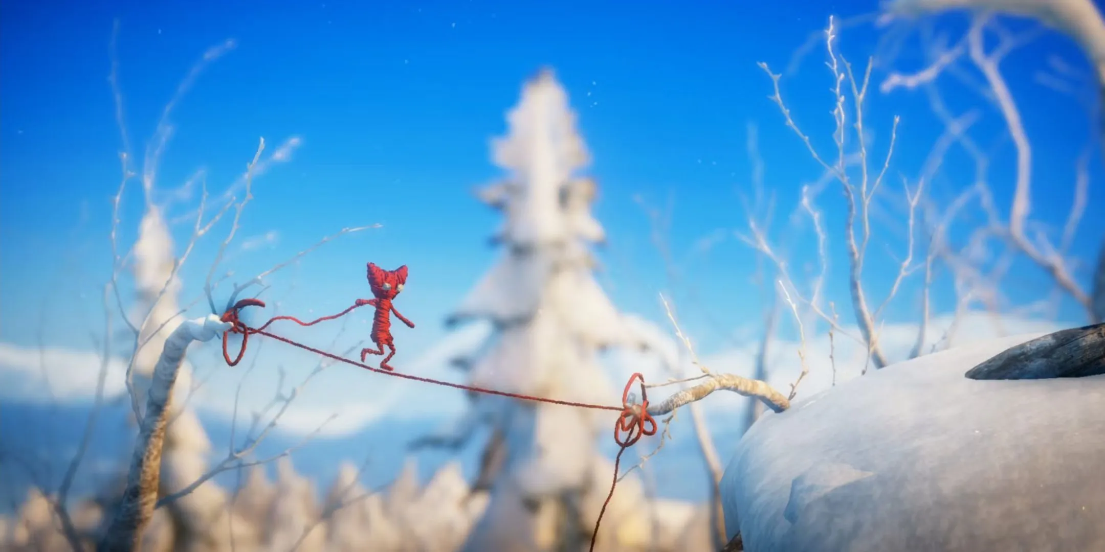 Nhân vật Yarny bằng len đỏ đang đi trên một sợi dây len trong Unravel
