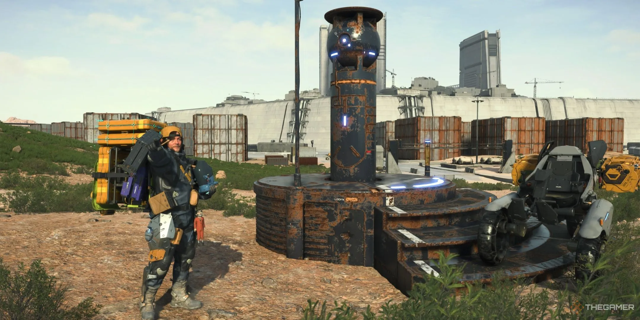 Sam tạo dáng cùng khoang BB trước một máy tự động phá hủy bị hỏng trong Death Stranding 2: On the Beach.