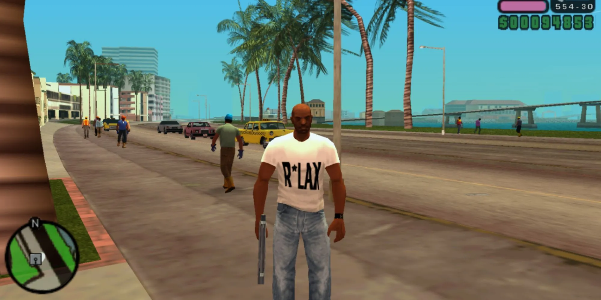 Victor Vance, nhân vật chính GTA Vice City Stories, đứng bên bờ biển với súng, thể hiện không gian thế giới mở rộng lớn của game trên PSP
